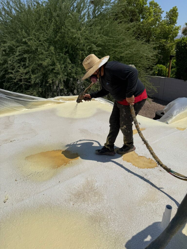Tip Top Roofing Service roofer spraying foam on a flat roof