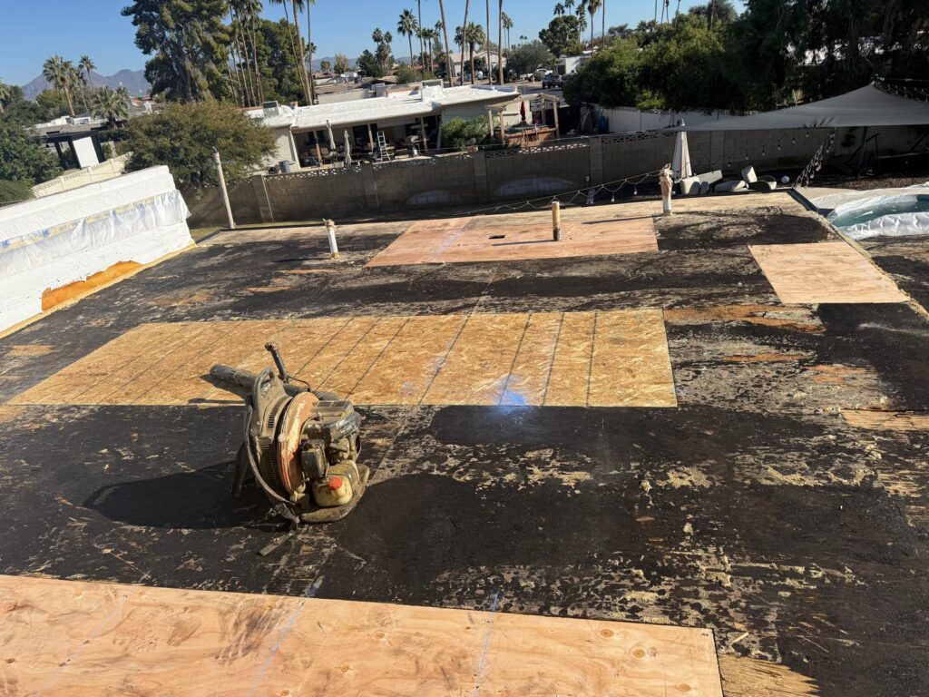 Flat roof deck with new plywood patches installed during repair, Tip Top Roofing Service